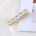 Détail d'une barrette en métal doré avec cinq cristaux carrés aux reflets irisés - Blanc Irisé