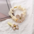 Dettaglio di elastico per capelli a fiori crema e clip abbinata su sfondo bianco - Avorio