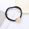 Detailed macro of golden heart charm with pink drop stone on black elastic hair tie - Pink