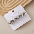 Dettaglio del fermaglio per capelli argentato a forma di cuore su carta decorativa - Cuore Argento Superficie Liscia