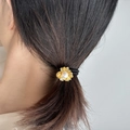 Detailansicht eines goldenen Blumen-Haargummis mit weißer Perle an einem Pferdeschwanz - Gold