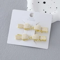 Ensemble de barrettes noeuds dorés avec perles blanches sur carte de présentation - Style Noeud