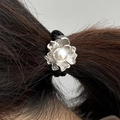 Nahaufnahme eines Lotus-Perlen-Haargummis mit silbernen Blüten auf dunklem Haar - Silber
