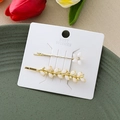 Vue détaillée de deux barrettes dorées avec des fleurs blanches et des strass brillants - Or Combo Épi