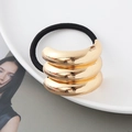 Nahaufnahme eines drelagigen goldenen Metall-Haargummis mit schwarzem elastischem Band - Gold Dreifach Halbrund