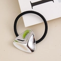 Close-up of a minimalist black hair tie featuring a polished triangle metal buckle detail - White Triangle