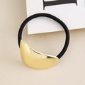 Detail shot of a minimalist gold crescent moon charm on a black elastic hair tie - Gold