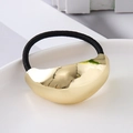 Macro shot of polished gold metallic curved hair tie with black elastic band on white plate - Gold Large Round Smooth