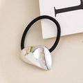 Close-up of silver irregular geometric metal charm on a black elastic hair tie - White