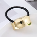 Close-up of golden wavy metal decoration on high-elastic black hair tie with mirror finish - Gold Smooth Wave