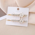 Détail de pinces à cheveux florales avec strass étincelants sur base dorée - Blanc