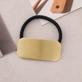 Macro detail of high-elastic black hair tie with premium brushed gold metal rectangle plate - Frosted Gold Square