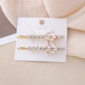 Détail de deux barrettes à fleurs en cristal avec pierres roses sur base dorée - Rose