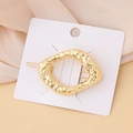 Lava texture geometric gold hair clip with vintage hammer finish on a pleated fabric base - Hammered Rectangle
