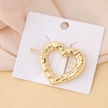 Detail of a golden heart hair clip with a hammered metal texture on a white display card - Hammered Heart
