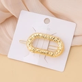 Detail of minimalist gold oval hair clip with hammered metal texture on white card - Hammered Oval