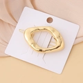 Macro detail of a minimalist gold irregular liquid metal hair clip on a white card display - Smooth Rectangle