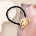 Détail d'un charm crabe doré en métal sur un élastique à cheveux noir haute élasticité - Crabe