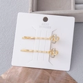 Elegante goldene Haarspangen mit Strasssteinen und Perlen auf weißer Displaykarte - Gold Kleine Strass Linien Kombination