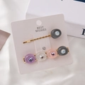 Détail de deux barrettes dorées avec des perles en résine colorées et de petits strass fins - Noir