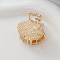 Detailed close-up of golden shell hair claw with starfish and fine textured metal finish - Shell