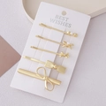 Dettaglio di cinque fermagli per capelli a fiocco in oro opaco con perle su espositore - Collezione Fiocco Oro Opaco