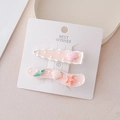Detalle de pinzas rosas con dijes de estrella de mar y conchas sobre cartón blanco - Estilo Concha Rosa