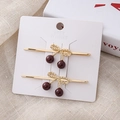 Dettaglio di fermagli per capelli a ciliegia rossa con fiocchi dorati su cartoncino - Rosso E Oro