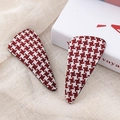 Macro view of red and white houndstooth fabric hair clips on a textured background - Red Triangle