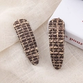 Close-up of retro houndstooth tweed BB hair clips in brown and beige on fabric - Coffee Water Drop