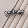 Macro view of gunmetal flower hair clip featuring grey pearls and sparkling rhinestones - Grey Pearl Hollow Flower Style