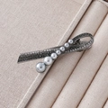 Detail of vintage gray pearl hair clip with rhinestones on beige jewelry display case - Grey Gradient Pearl Barrette Style