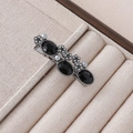 Detailed close-up of retro black gemstone hair clip with grey pearls in a jewelry box - Black Oval Gem & Metal Carving Style