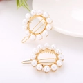 Elegant pair of gold alloy round hair clips featuring white faux pearls on white table - Circle 1 Gold
