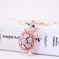 Golden turtle keychain featuring sparkling pink and white rhinestones on a book - Champagne