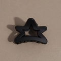 Detailed macro view of a matte black star-shaped hair claw clip on a brown surface - Pentagram / Black