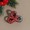 Detail showing Christmas floral hair claw with red and green gradient and snowflake dots - Bow
