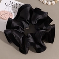 Macrodetail van de elegante zwarte fluwelen scrunchie met glanzende satijnen bies - Zwart