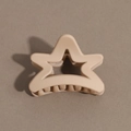 Macro shot of matte beige star-shaped hair claw clip with cutout design on textured background - Pentagram / Nude