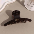 Detail view of handmade tortoiseshell hair claw clip with golden lettering and glossy finish - Dark Brown