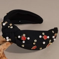 Detail of black knotted headband featuring pearls, rhinestones and red paw print charms - Black