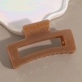 Macro shot of a glossy brown rectangular claw clip with hollow design and smooth finish - Brown