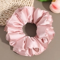 Close-up of pink satin scrunchie with soft waves and silky texture on a neutral background - Pink