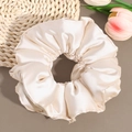 Detailed view of large cream satin scrunchie with soft silk texture and elegant pleats - Off White