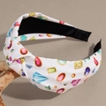 Close-up of a white knotted headband featuring vibrant gemstone prints on a wooden branch - Gemstone Print Style