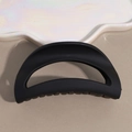 Detail of a large matte black hair claw clip resting on a white pearlescent cloud tray - Black