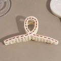 Detail view of cream jelly hair claw clip with brown dashed lines and gold metal spring - White