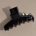 Macro shot of black glossy hair claw clip featuring sparkling teardrop crystals and rhinestones - Black