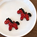 Gros plan de barrettes à cheveux cheval en strass rouges et noirs sur assiette blanche - Cheval Rouge
