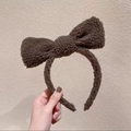 Detail of soft brown sherpa fleece headband featuring a large plush bow decoration - Brown